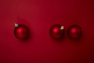 Kırmızı arka planda kırmızı noel topu süslemesi ve fotokopi alanı. Yeni yıl tebrik kartı. Asgari biçim