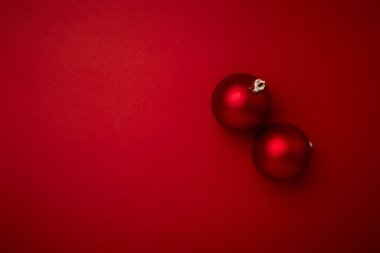 Kırmızı arka planda kırmızı noel topu süslemesi ve fotokopi alanı. Yeni yıl tebrik kartı. Asgari biçim