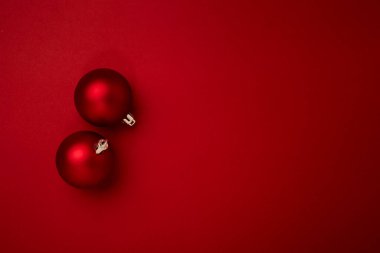 Kırmızı arka planda kırmızı noel topu süslemesi ve fotokopi alanı. Yeni yıl tebrik kartı. Asgari biçim