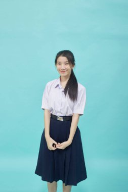 Young Asian student girl high school in student uniform on light blue studio isolated background clipart