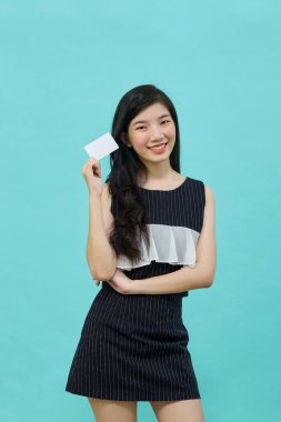 Genç, güzel Asyalı bir kadın gülümsüyor, gösteriyor, kredi kartı sunuyor.