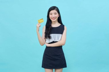 Genç, güzel Asyalı bir kadın gülümsüyor, gösteriyor, kredi kartı sunuyor.