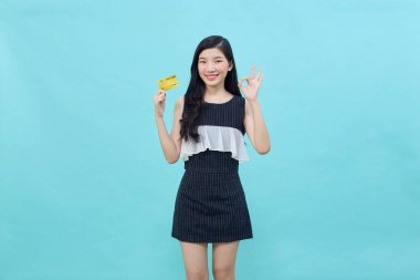 Genç, güzel Asyalı bir kadın gülümsüyor, gösteriyor, kredi kartı sunuyor.