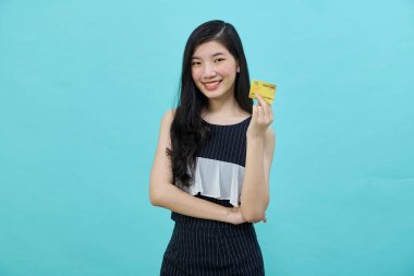 Genç, güzel Asyalı bir kadın gülümsüyor, gösteriyor, kredi kartı sunuyor.