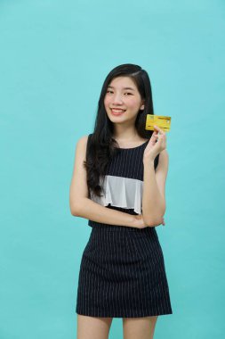 Genç, güzel Asyalı bir kadın gülümsüyor, gösteriyor, kredi kartı sunuyor.