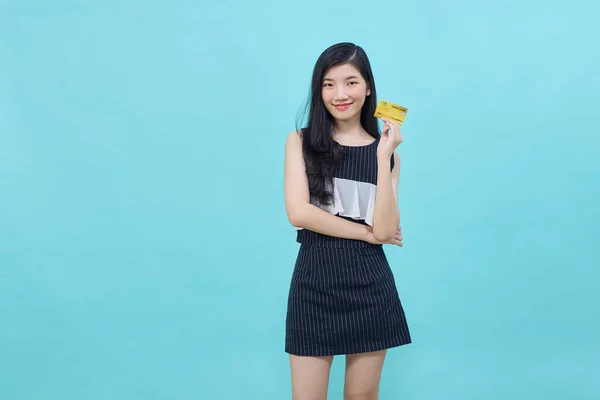 若い美しいアジアの女性は 青色の背景に支払いやオンラインビジネスを支払うためのクレジットカードを提示し — ストック写真