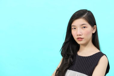 Asyalı iş kadını iktidarda duruyor. Profesyonel iş adamı mavi arka planda duruyor.