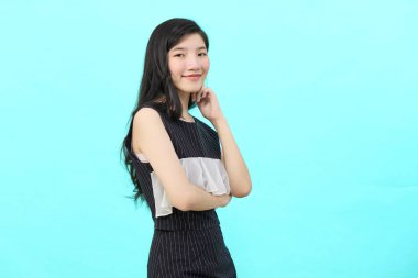 Asyalı iş kadını iktidarda duruyor. Profesyonel iş adamı mavi arka planda duruyor.