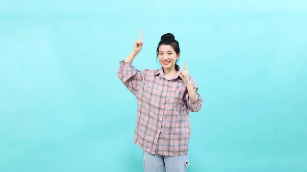 青い背景に幸せと自信を感じて立っている再生シャツを着て広告を見てかなりポインティング若いアジアの女性 — ストック写真