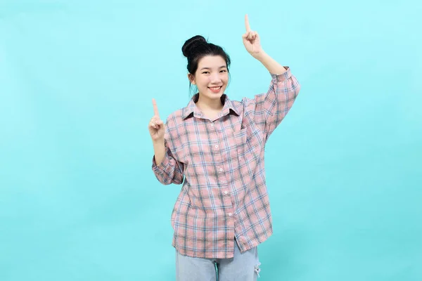 青い背景に幸せと自信を感じて立っている再生シャツを着て広告を見てかなりポインティング若いアジアの女性 — ストック写真