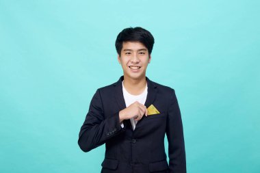 Mavi bir stüdyoda izole edilmiş sarı kredi kartı taşıyan takım elbiseli yakışıklı bir iş adamı portresi