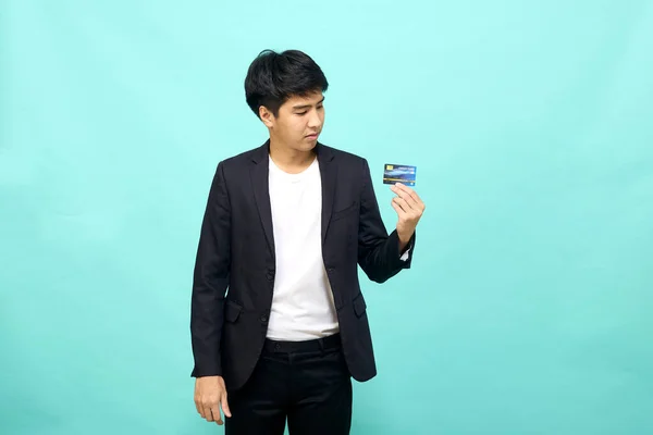 年轻商人在孤立的蓝色背景下手持和展示信用卡的肖像 — 图库照片