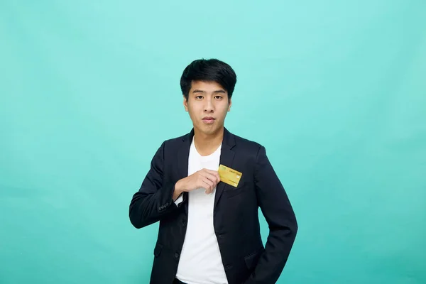 肖像画青いスタジオに隔離された黄色のクレジットカードを保持するスーツで若いハンサムなビジネスマン — ストック写真