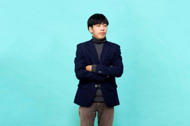 Genç Güneydoğu Asyalı, mutlu ve kendine güveni tam, hafif mavi stüdyoda çapraz kollu, kendine güvenen bir adam.