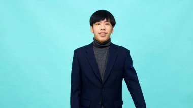 Genç Güneydoğu Asyalı, mutlu ve kendine güveni tam, hafif mavi stüdyoda çapraz kollu, kendine güvenen bir adam.