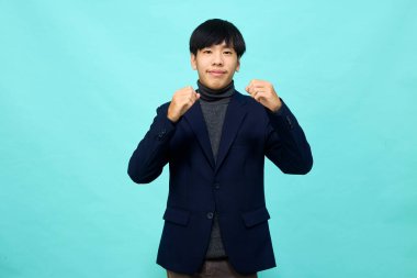 Genç Güneydoğu Asyalı, mutlu ve kendine güveni tam, hafif mavi stüdyoda çapraz kollu, kendine güvenen bir adam.