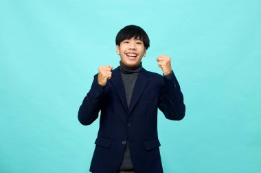 Genç Güneydoğu Asyalı, mutlu ve kendine güveni tam, hafif mavi stüdyoda çapraz kollu, kendine güvenen bir adam.