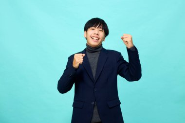 Genç Güneydoğu Asyalı, mutlu ve kendine güveni tam, hafif mavi stüdyoda çapraz kollu, kendine güvenen bir adam.