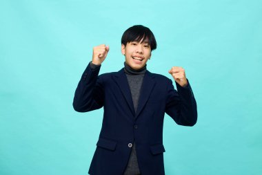 Genç Güneydoğu Asyalı, mutlu ve kendine güveni tam, hafif mavi stüdyoda çapraz kollu, kendine güvenen bir adam.