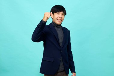 Genç Güneydoğu Asyalı, mutlu ve kendine güveni tam, hafif mavi stüdyoda çapraz kollu, kendine güvenen bir adam.