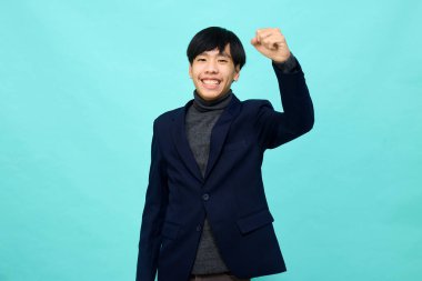 Genç Güneydoğu Asyalı, mutlu ve kendine güveni tam, hafif mavi stüdyoda çapraz kollu, kendine güvenen bir adam.