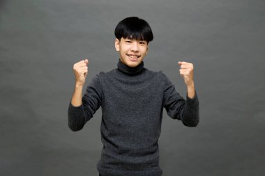 Genç yakışıklı Asyalı adam gri izole arkaplanda yer kopyalamak için poz veriyor.