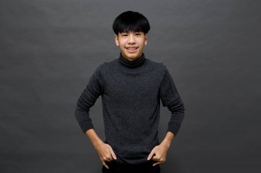 Genç yakışıklı Asyalı adam gri izole arkaplanda yer kopyalamak için poz veriyor.