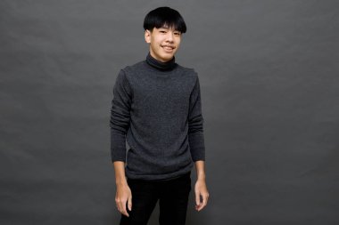 Genç yakışıklı Asyalı adam gri izole arkaplanda yer kopyalamak için poz veriyor.