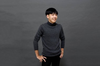 Genç yakışıklı Asyalı adam gri izole arkaplanda yer kopyalamak için poz veriyor.