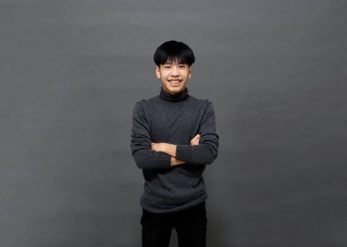 Genç yakışıklı Asyalı adam gri izole arkaplanda yer kopyalamak için poz veriyor.