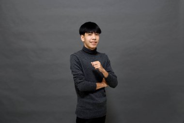 Genç yakışıklı Asyalı adam gri izole arkaplanda yer kopyalamak için poz veriyor.