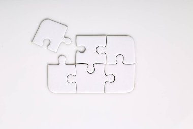 Beyaz arkaplanda dört beyaz yapboz parçası var. Beş tanesi zaten birleştirilmiş. Birleştirmek için bir parçası eksik.