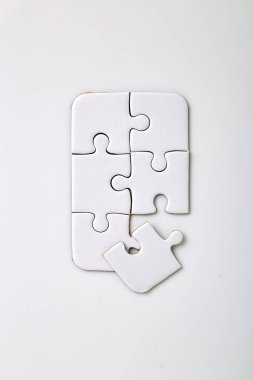 Beyaz arkaplanda dört beyaz yapboz parçası var. Beş tanesi zaten birleştirilmiş. Birleştirmek için bir parçası eksik.