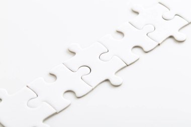 Beyaz arka planda altı beyaz yapboz parçası farklı elementleri bir bütün haline getiriyor.