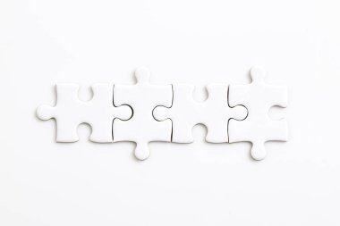 Beyaz arkaplanda dört beyaz yapboz parçası farklı elementleri bir bütün halinde birleştiriyor.