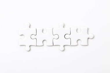 Beyaz arkaplanda dört beyaz yapboz parçası farklı elementleri bir bütün halinde birleştiriyor.