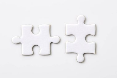 Beyaz arka planda iki beyaz yapboz parçası. İki parça birleşiyordu.