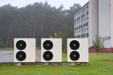Bir apartmanın önünde Isıtma ve Sıcak Su İçin Hava-Sıcaklığı Pompası