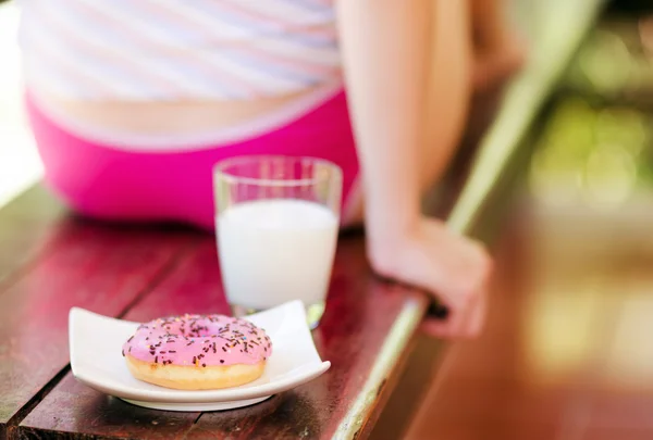 Mujer joven sentada en la terraza con leche y donut —  Fotos de Stock