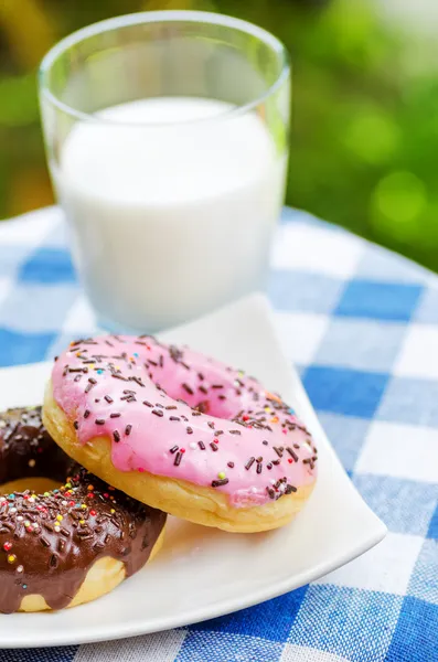 Donuts frescos y vaso de leche en el fondo de la naturaleza — Foto de Stock