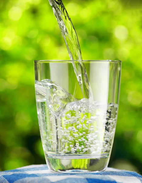 Vidro de água no fundo da natureza — Fotografia de Stock