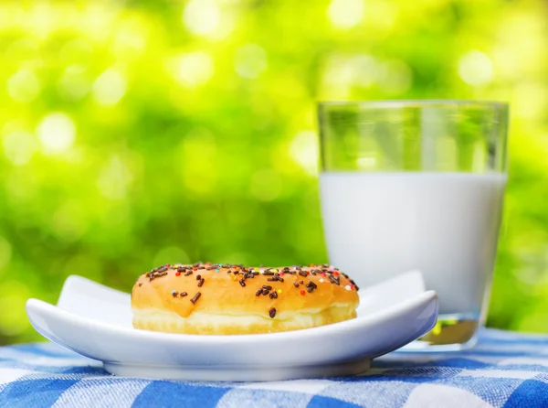 Fresh donut and glass of milk on nature background — Stock Photo, Image