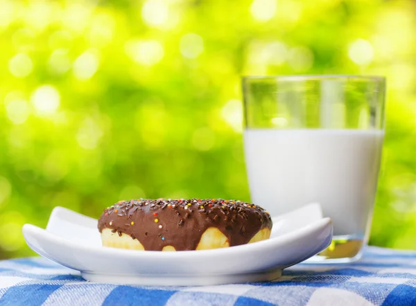 Fresh donut and glass of milk on nature background — Stock Photo, Image