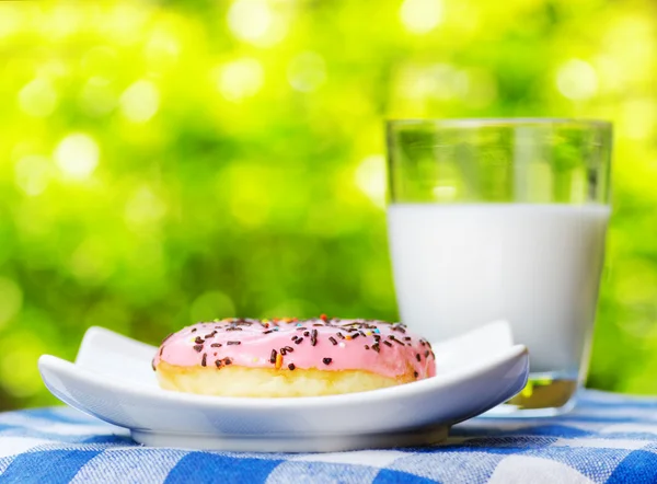 Donut fresco y vaso de leche sobre fondo natural — Foto de Stock