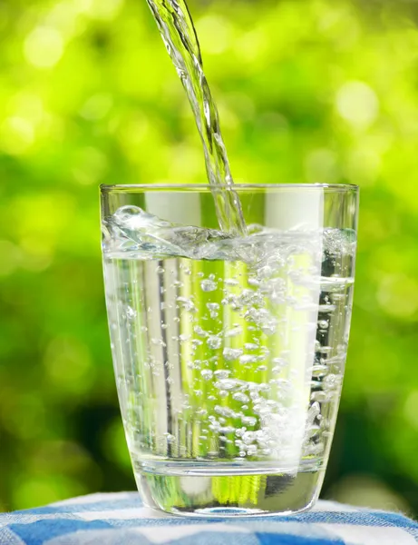 Szklanka wody na tle przyrody — Zdjęcie stockowe