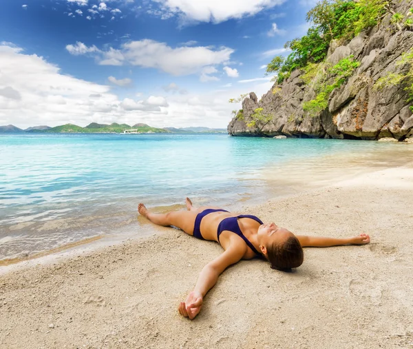 Jovem mulher bonita está relaxando na areia junto ao mar — Fotografia de Stock