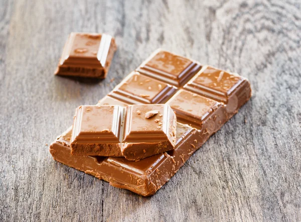 Broken chocolate on wooden table — Stock Photo, Image