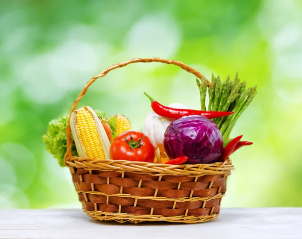 Färska grönsaker i korgen på träbord — Stockfoto