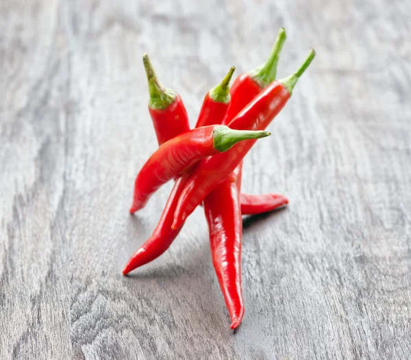 Red chilli peppers on wooden table — Stock Photo, Image