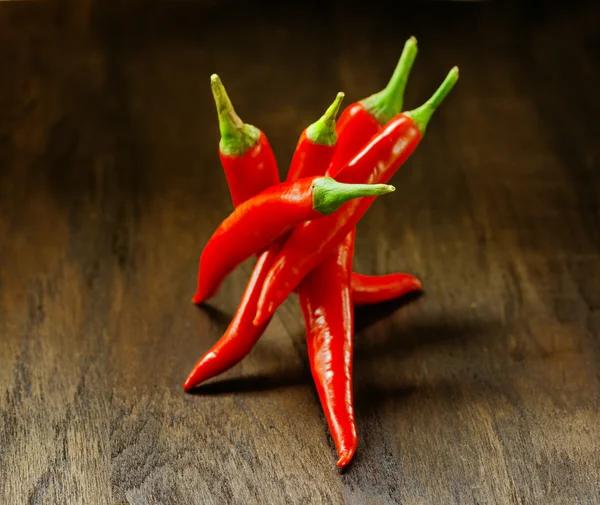 Red chilli peppers on wooden table — Stock Photo, Image